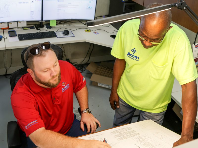 Acom staff planning over system drawings