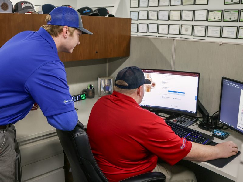 Acom staff coaching a colleague at a workstation