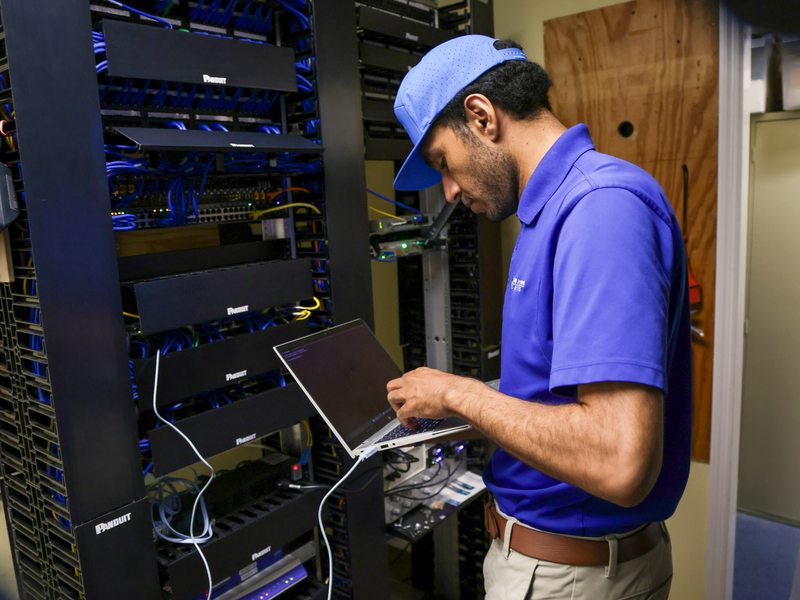 Technician configuring network equipment at a rack