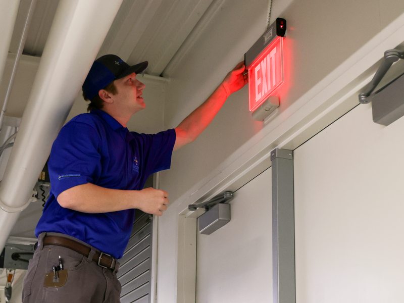 Technician testing an illuminated exit sign