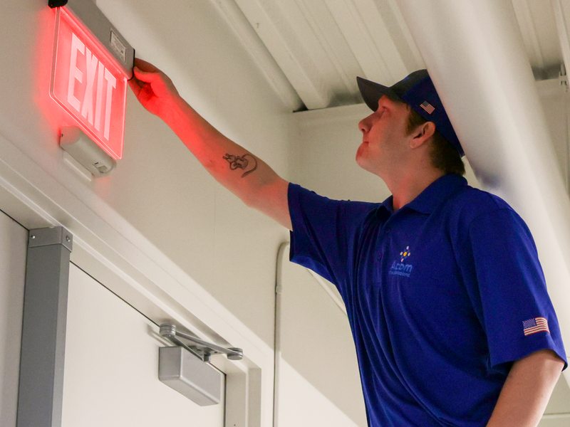 Technician checking exit signage along the egress path