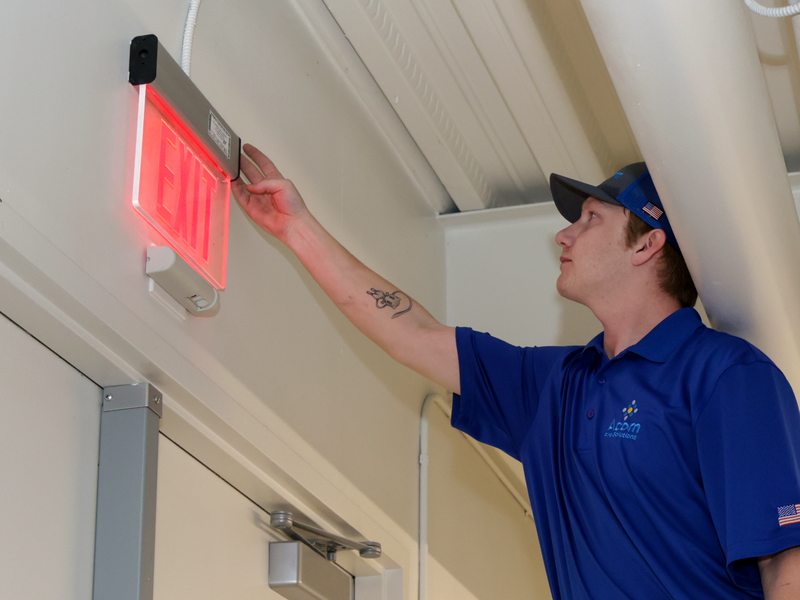Technician inspecting an edge-lit exit sign