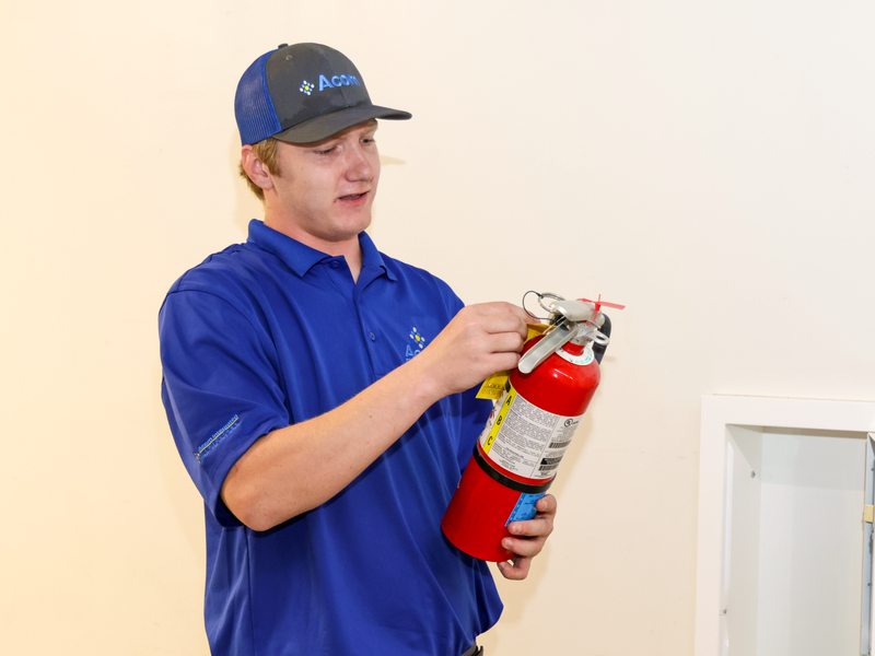 Technician checking pin and gauge on an extinguisher