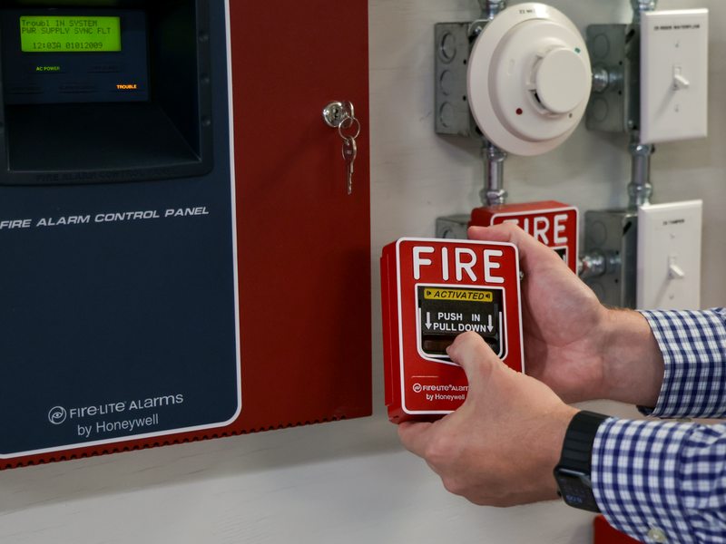 Hands resetting a fire alarm pull station