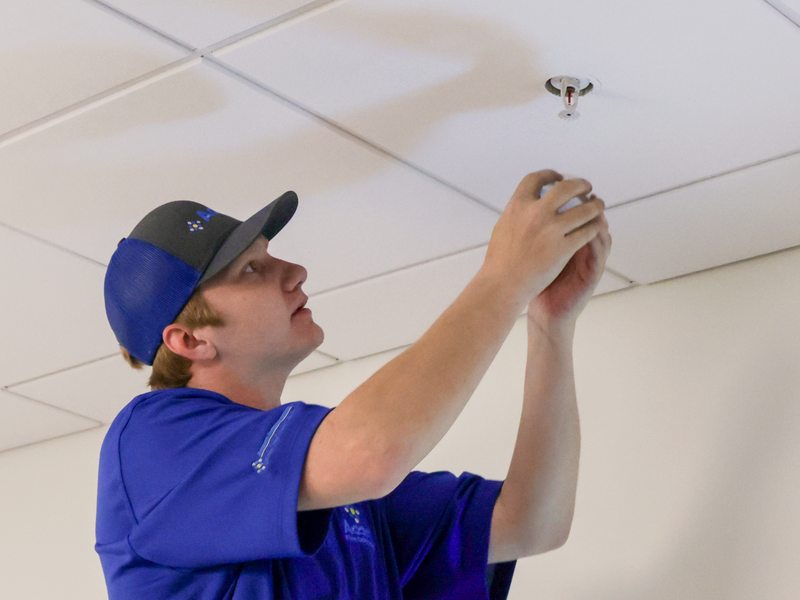 Technician adjusting a pendant sprinkler head