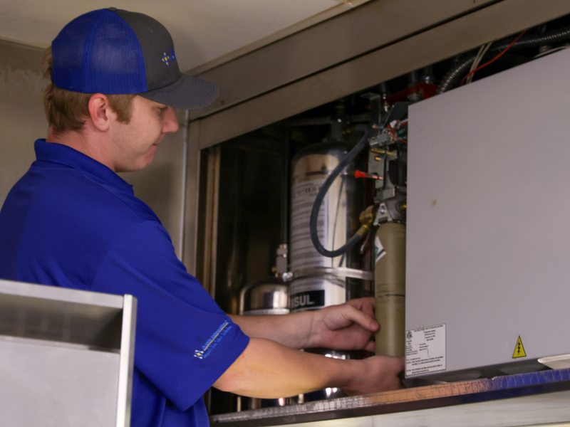 Technician inspecting the wet-chemical suppression tank cabinet