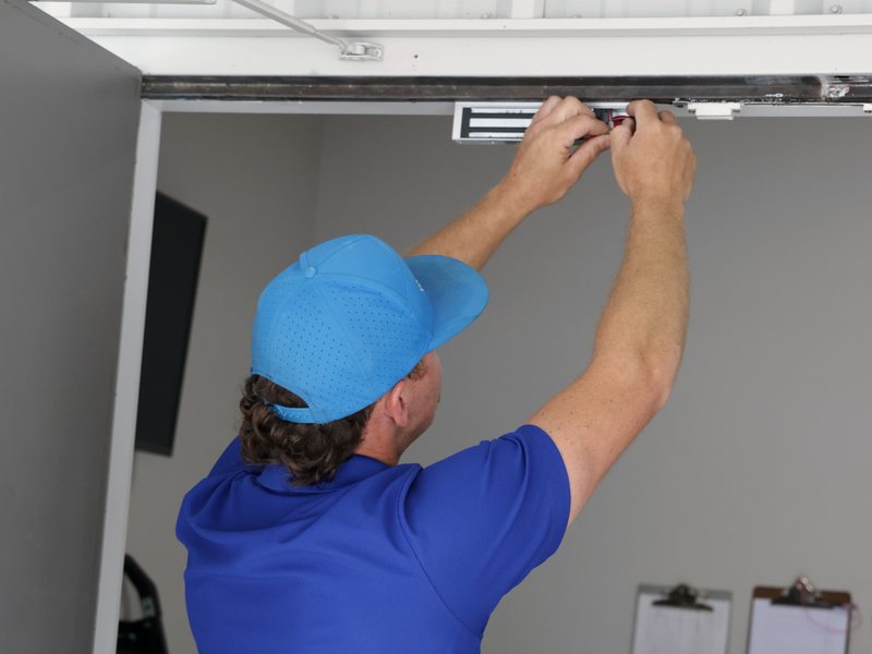 Technician installing a smart magnetic lock above a door