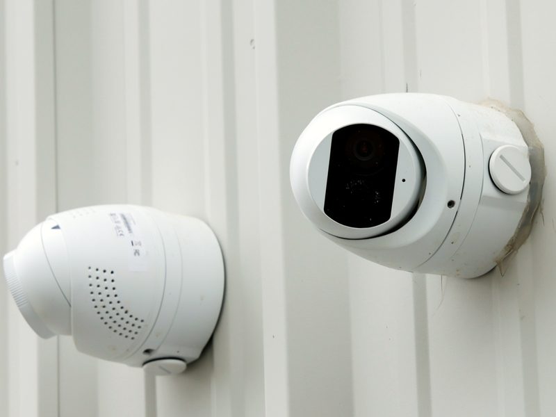 Visible security camera and warning speaker mounted on a building