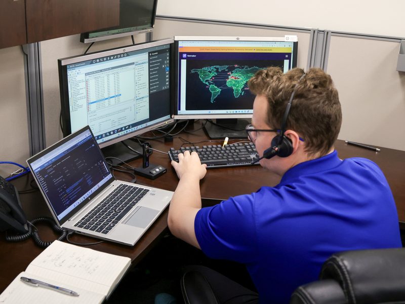 Monitoring operator with headset at multi-monitor station