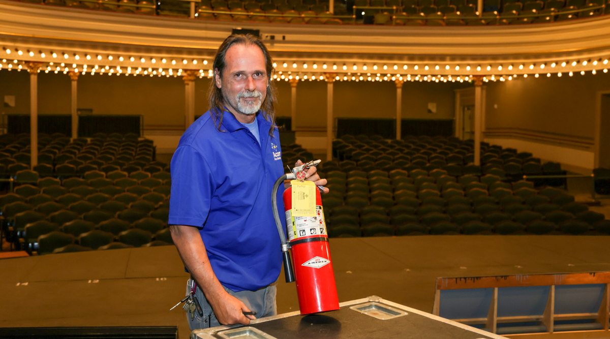 Smiling Acom technician with a serviced extinguisher