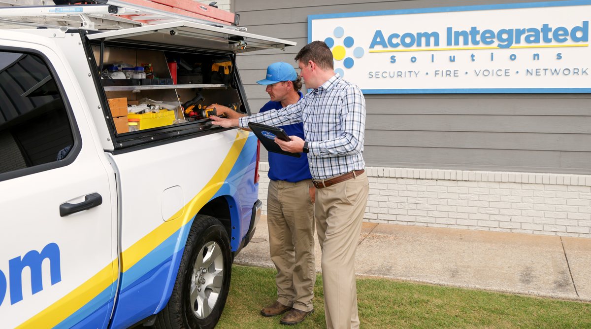 Store operations manager reviewing a security system with an Acom technician